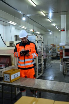 Factory technician monitoring food processing machinery in an industrial facility.