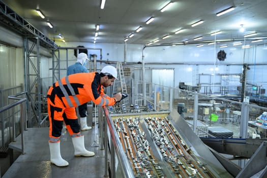 Factory inspector monitoring canned goods moving on a conveyor line in a food processing plant.