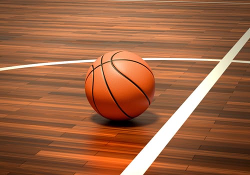 An official orange basketball ball on a hardwood basketball court