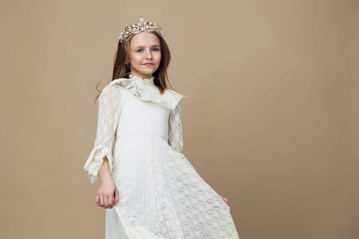 A charming young girl wearing a white lace dress and a crown, exuding joy and innocence Perfect for themes of childhood, celebration, and elegance, set against a soft beige background