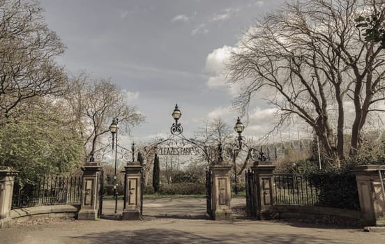 Newcastle, UK - Apr 13, 2025 - View of Cast iron lamp over the Wrought iron gate is open to the entrance of Leazes park with beautiful sky background. use it as your Wallpaper, Poster and Copy space, Selective focus.