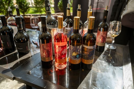 Odessa, Ukraine - April 05, 2025: Bottles of wine on a black table outdoors in a hotel. wine tasting at a city fair in soft natural light.