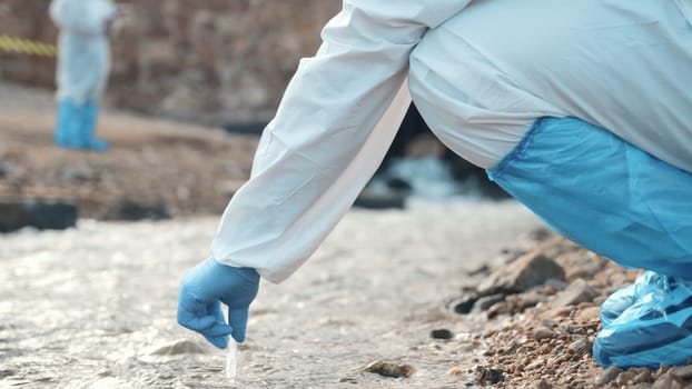 Ecologist sampling water from the river with test tube, Biologist wear protective suit and mask collects sample of waste water from industrial, problem environment, scientist environmentalist