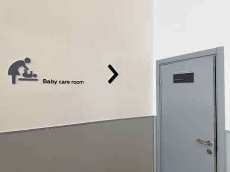 Wall sign for baby care room in public facility. Urban infrastructure and parental support concept with modern wayfinding. Neutral interior with clear direction for families and caregivers