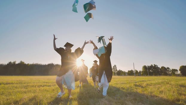 College graduates run into the sunset and throw books and notebooks up in the air
