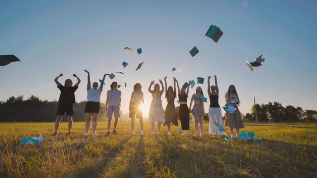 Group of joyful high school students tossing their notebooks into the air, celebrating the end of the school year and the beginning of summer vacation