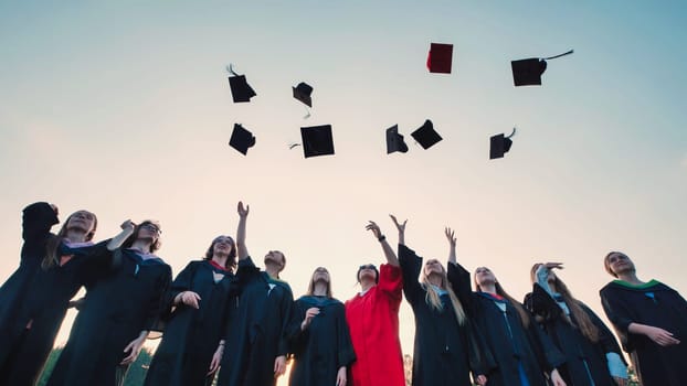 Happy graduates celebrating their achievement by throwing their caps into the air with a beautiful sunset as the backdrop
