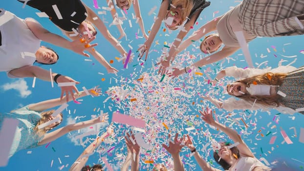 Group of cheerful high school students throwing colorful confetti in the air, celebrating graduation during summer