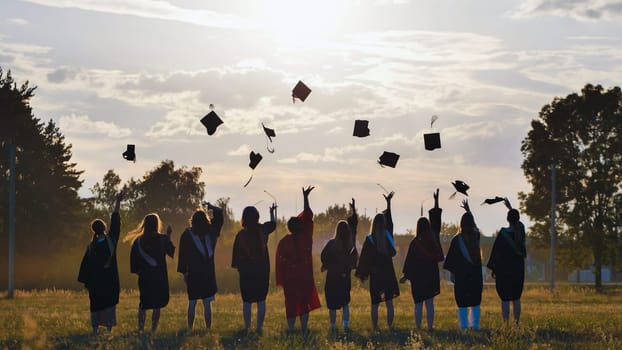 Group of graduates throwing graduation caps in the air at sunset, celebrating their academic achievement and the start of a new chapter in their lives