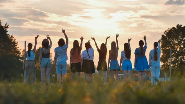 School friends waving goodbye at sunset, celebrating the joyful end of their school days together in a vibrant, grassy field