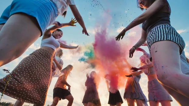 Young students celebrate the end of school by tossing colorful powder into the air as a group