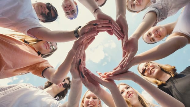 Group of students forming circle with their hands, symbolizing teamwork, friendship, and unity