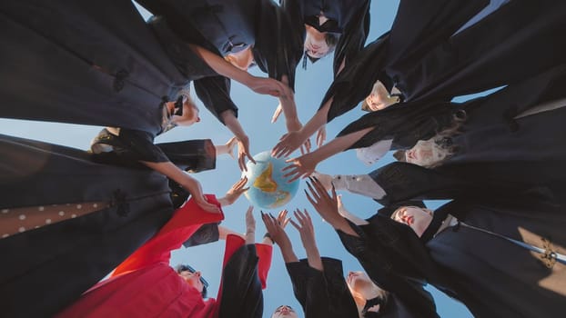 Group of graduates in academic gowns touching a globe, symbolizing their readiness to embrace global opportunities after their graduation ceremony