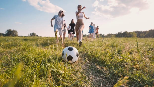 Group of school friends playing soccer running in a grass field during a sunny summer day