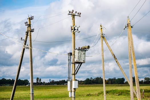 Old electricity poles and wires supplying electricity to the countryside under a cloudy sky