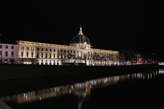 Majestic view of the Grand Hotel-Dieu in Lyon, France, captured at night with architectural lighting and traffic along the boulevard.