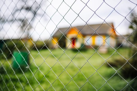 Chain link fence is blocking access to colorful house with green lawn