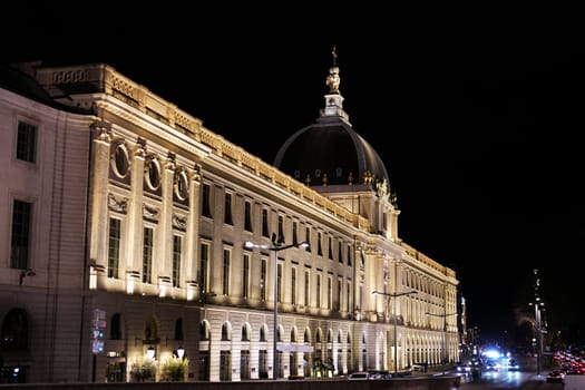 Majestic view of the Grand Hotel-Dieu in Lyon, France, captured at night with architectural lighting and traffic along the boulevard.