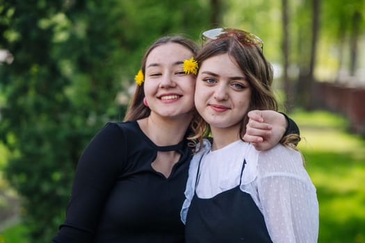 Two cheerful students hugging, enjoying their time together on a sunny day on school grounds