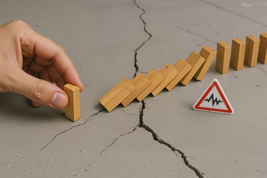 Finger tipping first domino causing chain reaction toward warning sign. AI generation.