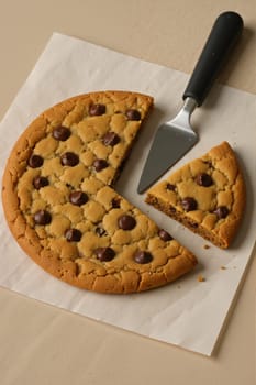 Spatula slicing large round cookie on paper. AI generation.