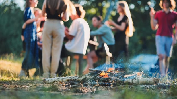 Group of students celebrating their graduation, gathered around a lively bonfire in a serene natural setting, enjoying friendship and joy