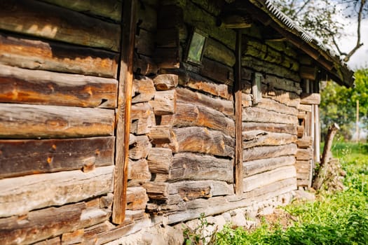 Weathered wood planks forming the wall of an old wooden house, showcasing rustic charm in a rural landscape