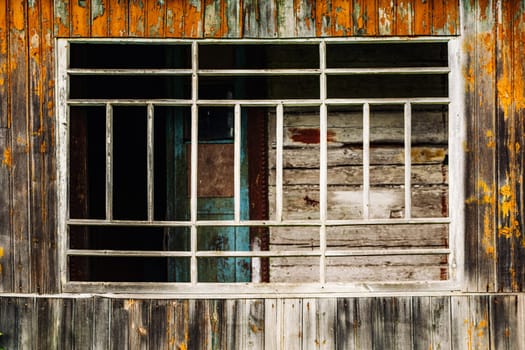 Barred window of abandoned building showing peeling paint and decay