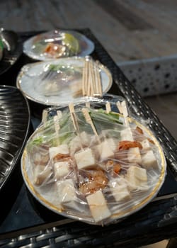 street food under transparent packaging on the street on the table. skewers with cheese, herbs and shrimps