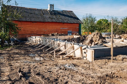 Building reinforced strip foundation for new house next to old wooden house