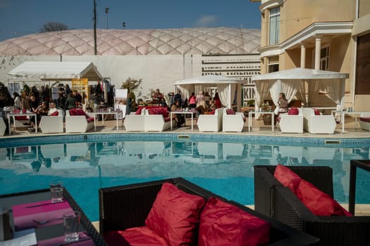 Odessa, Ukraine - April 05, 2025: City street food festival near the hotel in the pool area. Around the pool there are people and tables set for food.