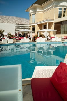 Odessa, Ukraine - April 05, 2025: City street food festival near hotel in swimming pool area. Around the pool people and tables for food. group of people sitting at a table in front of a building