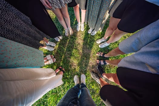 Friends standing together in a circle on green grass, showing unity and teamwork