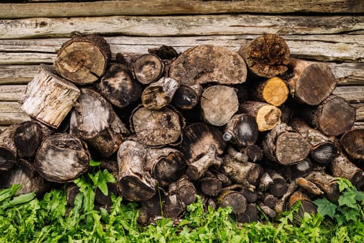 Firewood logs stacked against a wooden wall, ready for winter, providing warmth and fuel