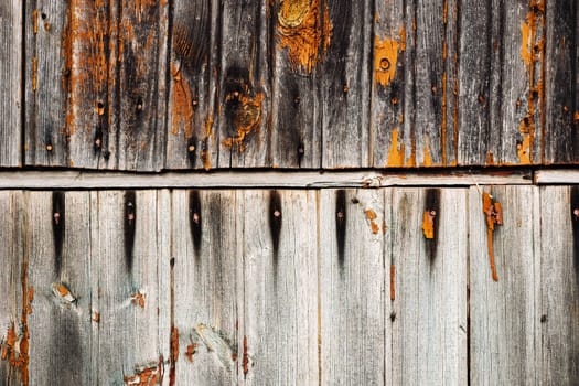Weathered wooden planks with peeling orange paint create a rustic, textured background, ideal for design projects needing a touch of vintage charm