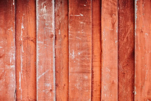 Weathered red wooden planks showing signs of age and wear, creating a rustic, textured background