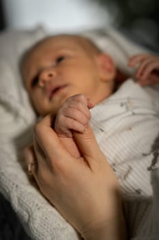 A mother gently holds her newborn babys tiny hand, showcasing a heartfelt connection in a warm and cozy environment filled with soft light.