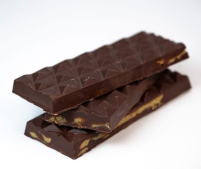 Stacked layers of kadaif embrace a generous coating of rich chocolate and are topped with a pistachio, showcasing the delightful texture and flavors in a culinary presentation.