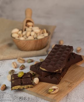 Gourmet chocolate mixed with crunchy kadaif pistachio pieces is beautifully presented on a wooden board, making a perfect treat in Dubai's culinary scene.