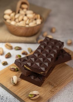 Gourmet chocolate mixed with crunchy kadaif pistachio pieces is beautifully presented on a wooden board, making a perfect treat in Dubai's culinary scene.