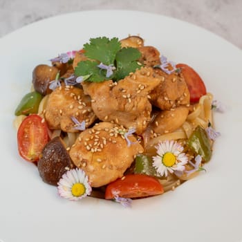 A flavorful blend of chicken, linguine, shiitake mushrooms, bell peppers, and fresh garden flowers offers a vibrant and appetizing meal. Ideal for a cozy dinner or gathering.