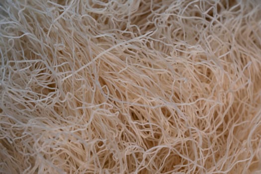 Delicate strands of kadaif are showcased in a lively kitchen, ready to be incorporated into a delicious traditional dessert. The warm lighting enhances the texture of the dough.