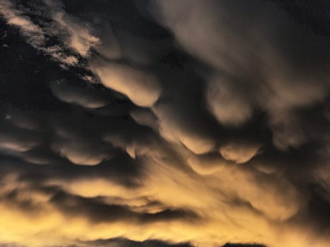 Storm clouds on sunset. Light in the dark and dramatic storm clouds. Background of storm clouds before a thunderstorm. Mammatus clouds. High quality photo