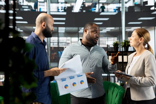 Upset manager berating employees, unsatisfied with progress done on customer commissioned project after reading company documents. Mad supervisor scolding workers, displeased by business audit results