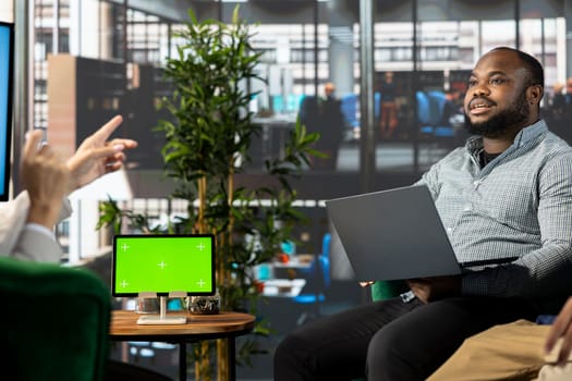 Staff members using green screen device, doing briefing meeting to share new ideas for profit growth. Group of employees in office workplace discussing with director, using chroma key tablet,