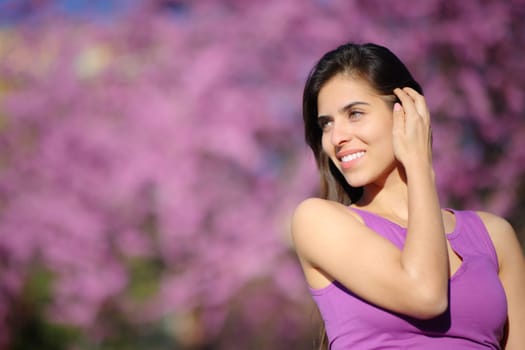 Beauty woman touching hair in a violet park looking at side