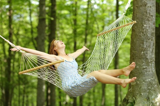 Happy woman swinging on hammock in spring in a forest