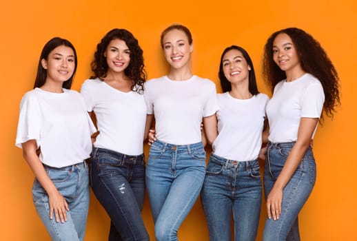 Group Of Five Diverse Models Ladies Posing Smiling To Camera Standing On Yellow Studio Background. Mixed Women Expressing Positive Emotions. Female Beauty And Diversity Concept
