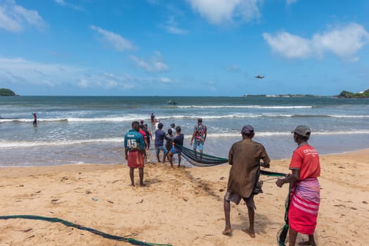 Galle, Sri Lanka - September 14 2024; Two men coming in through small surf in traditional fishing boat or 
oruwa at South Sri Lankan beach.
