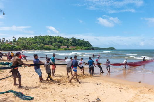 Galle, Sri Lanka - September 14 2024; Two men coming in through small surf in traditional fishing boat or 
oruwa at South Sri Lankan beach.
